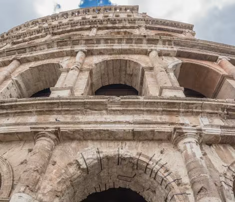 a grey colosseum beneath greyer skies in rome